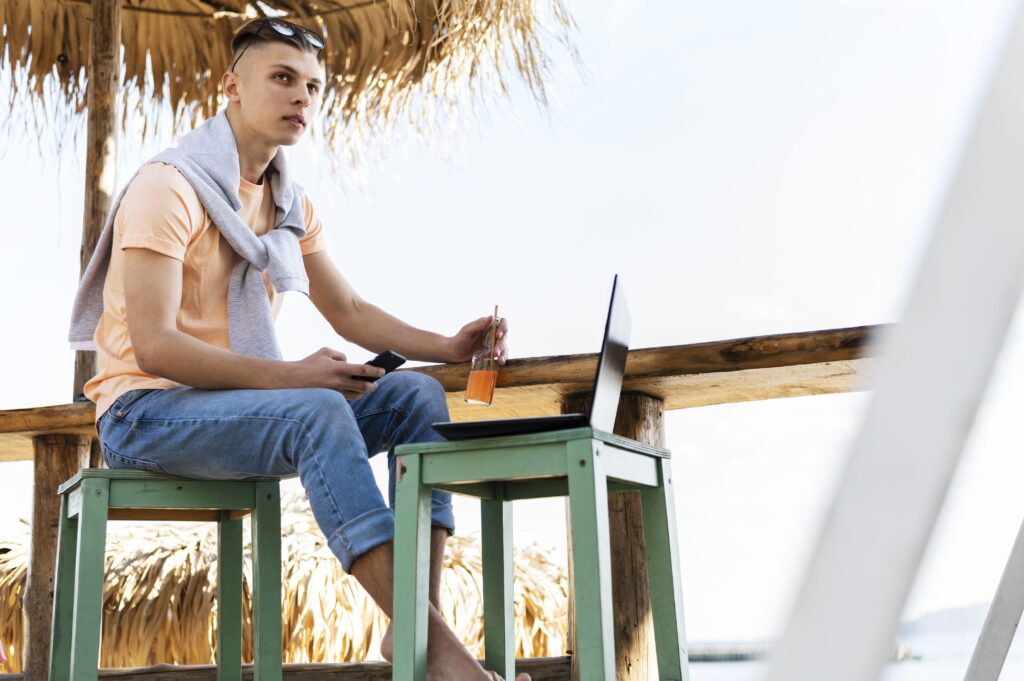 Entrepreneur travaillant sur son ordinateur en bord de mer, visa DTV entrepreneur ou salarié à distance